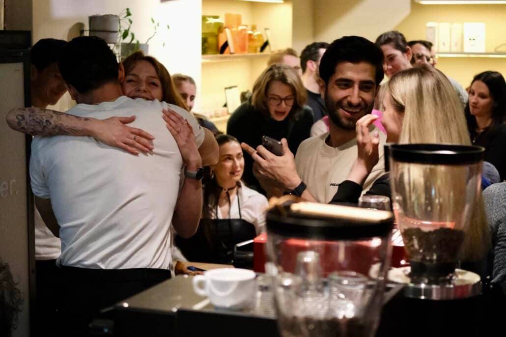 Die Gewinner umarmen sich, Zuschauer unterhalten sich im Hintergrund