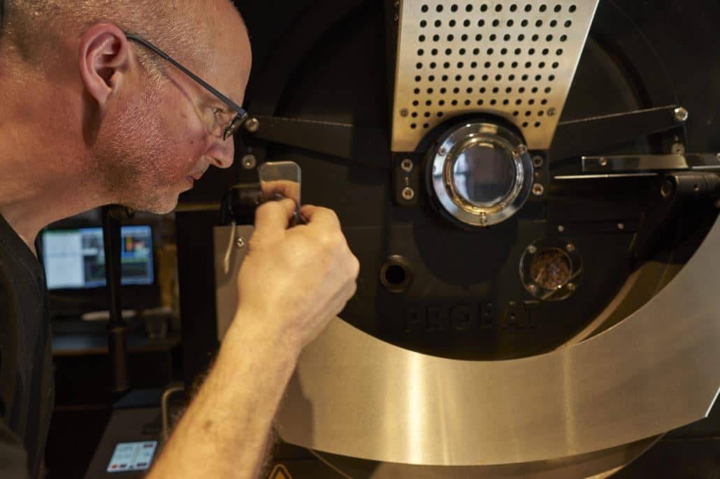 Ein Mann begutachtet die Kaffeeröstmaschine