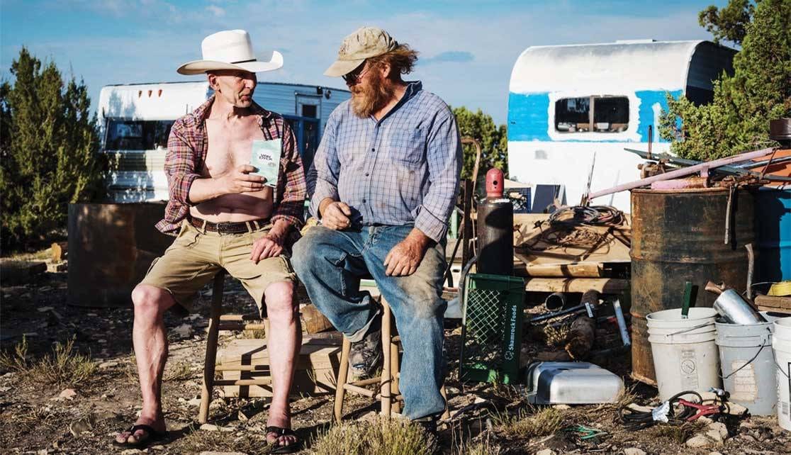Zwei Männer sitzen auf einem Hocker in Arizona und halten einen Kaffeebeutel in der Hand