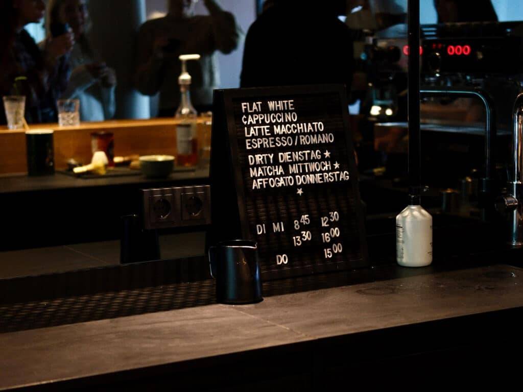 Eine Tafel auf einer Bar zeigt verschiedene Kaffeeangebote ohne Preise